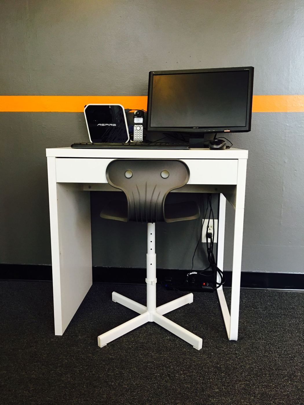 Technician workstation at the Fasthuma office: a white desk with a monitor, a small computer and a black chair